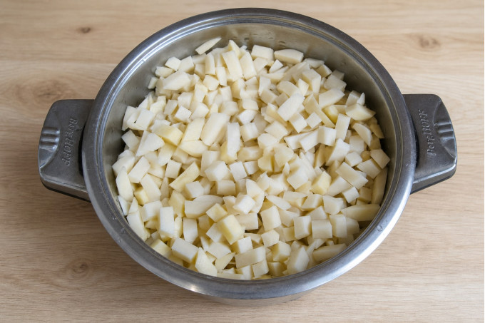 Очищенный сырой картофель, нарезанный кубиками, в кастрюле перед бланшировкой